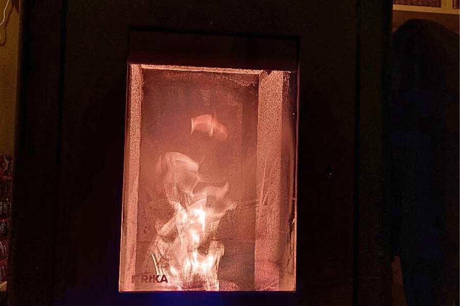 Der Pelletofen im Flur mit einer hohen Flamme hinterm Sichtfenster