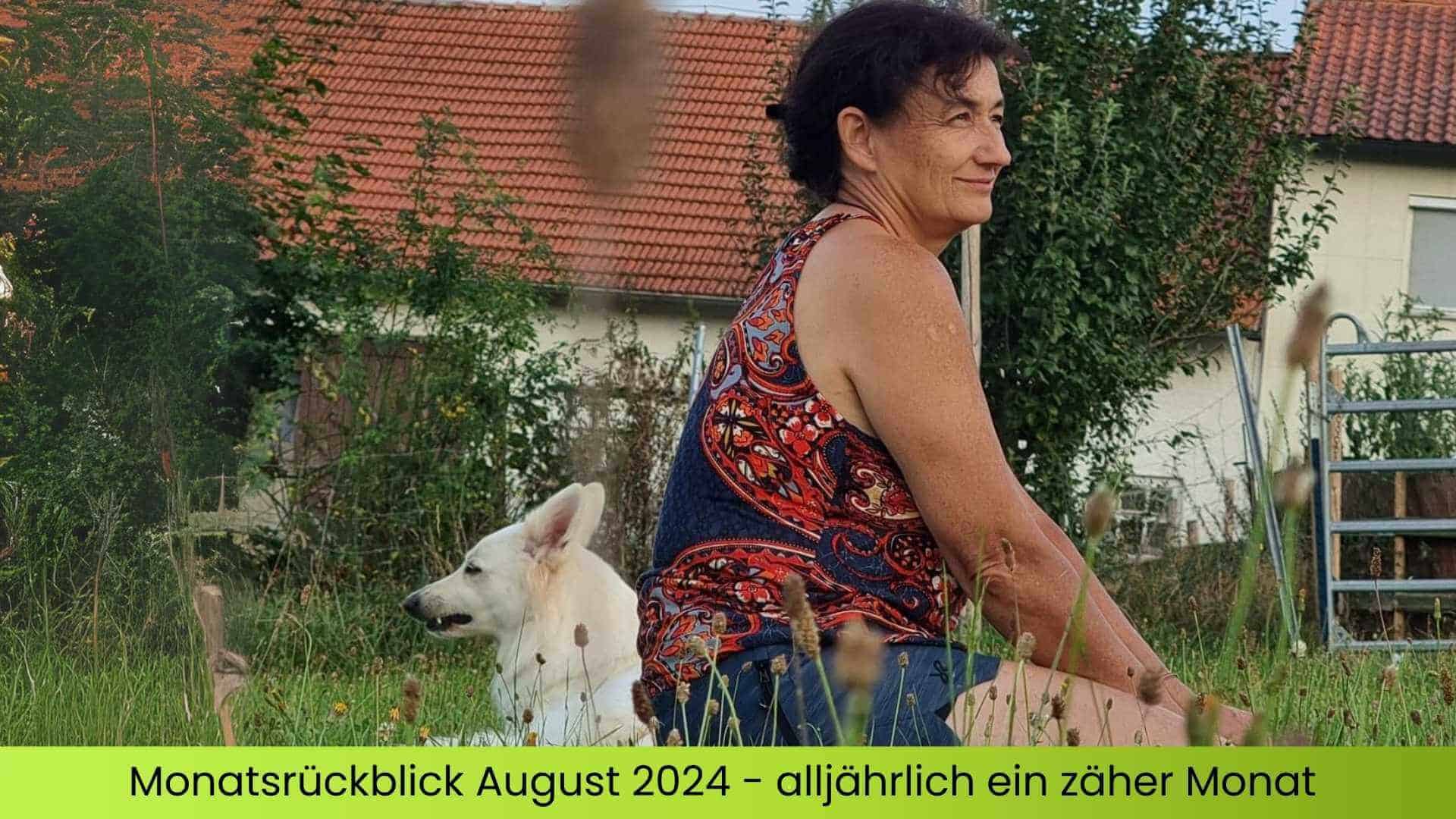 Marianne sitzt im Gras hinter ihr ein weißer Schäferhund.