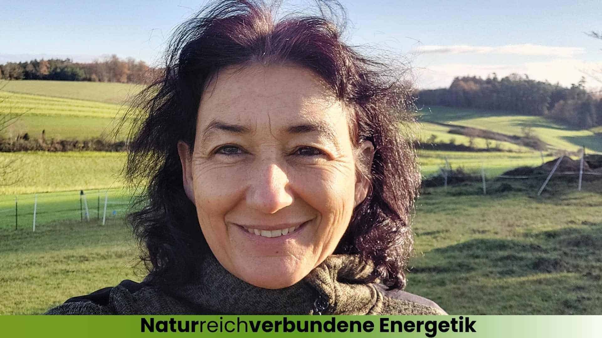 Marianne lächelnd draußen auf der Weide im Hintergrund die grüne Landschaft